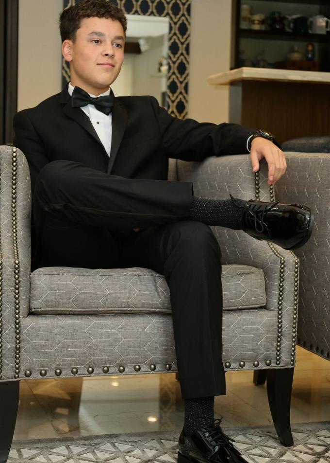 A young man in a black tuxedo and bow tie, dressed for the night